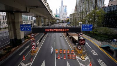 2022年3月28日，上海封城期间限制高速公路交通，一名身穿防护服的工人在通往黄浦江对面浦东地区的隧道入口处行走。（图取自路透社档案照）