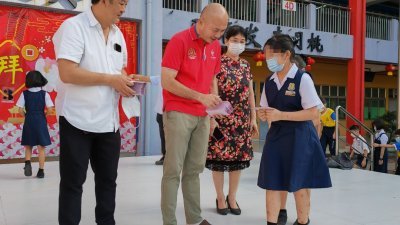 林立迎（中）派发红包给学生。左起为甲二家协主席苏子贤和钱秀芬校长。