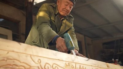 棺材制造厂内，熟练的工匠在新砍的木头上雕刻精美的装饰。（图取自BBC）