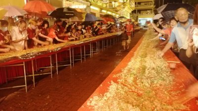 逾千人在雨中撑伞捞生，加上688尺长的捞生桌，场面十分壮观。