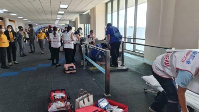 泰国一名妇女周四在曼谷廊曼机场的电动步道发生意外，徒步卷入机器中，救护人员在现场协助她脱困。（图取自泰国廊曼国际机场面子书）