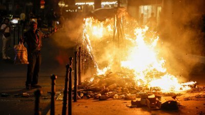 席卷法国各大城市的暴力骚乱在周五进入第4天，在巴黎街头，一名男子在燃烧的容器旁边表情显得无奈。（图取自路透社）