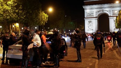 在法国巴黎著名的香榭丽舍大道区域，警方在周日凌晨扣押示威者。（图取自路透社）