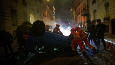 在法国巴黎，防暴警察和急救人员在周日移动一辆遭示威者掀翻，挡在路中央的车子。（图取自路透社）
