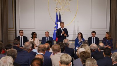 法国总统马克龙（站立者）当地时间周二在巴黎爱丽舍宫，会晤受暴力冲突影响的城市市长。（图取自法新社）