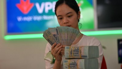 一名银行员工在河内VPBank分行检查纸币。当局6月29日表示，由于出口受到需求下滑的影响，越南上半年经济增长放缓。（图取自法新社）