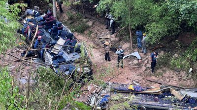巴士周三在墨西哥瓦哈卡州马格达莱纳佩纳斯科镇坠落峡谷，严重受损，警方和救护人员在现场善后。（图取自路透社）