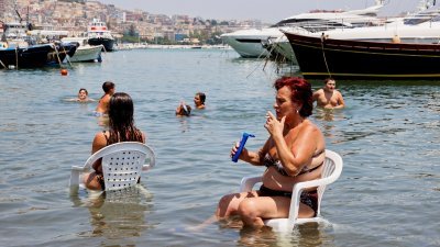 热浪席卷意大利那不勒斯，一名妇女当地时间周一坐在海里降温避暑。（图取自路透社）