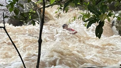 18岁的巫裔少年在山洪爆发后被困在激流中，过后被消拯员以救生绳索救上岸。