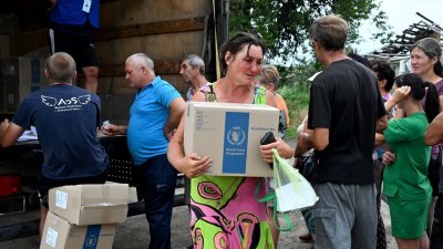 在乌克兰伊久姆镇附近的Topolske村，当地村民上周六从世界粮食计划署 (WFP) 的志工手中领取派发的援助食品。（图取自法新社）