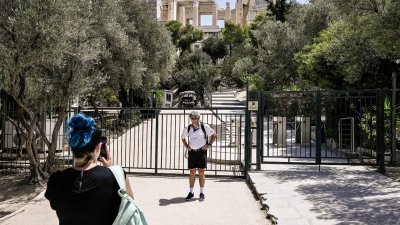 希腊最著名的景点雅典卫城周五因热浪暂时关闭，游客无奈只能站在已关上的入口处前拍照。（图取自法新社）