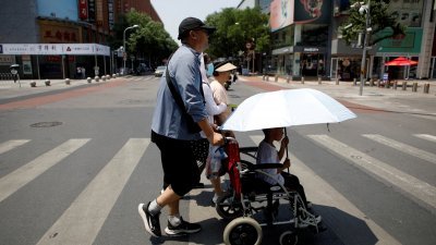 图为北京上周日发布炎热天气橙色警报，市民全副“装备”出行。（图取自路透社）

