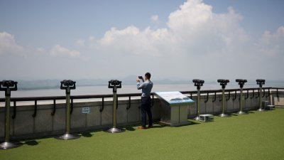 在韩国坡州，一名男子周三在分隔韩朝两国的非军事区附近的观察平台上拍摄朝鲜领土的照片。（图取自路透社）