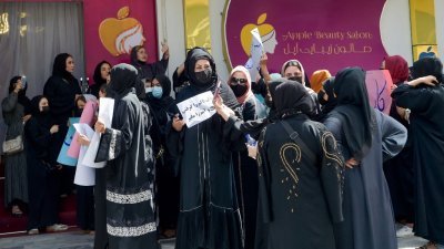 阿富汗妇女周三在喀布尔Shahr-e-Naw地区的一家美容院外举行抗议活动，争取自己的权利。（图取自法新社）