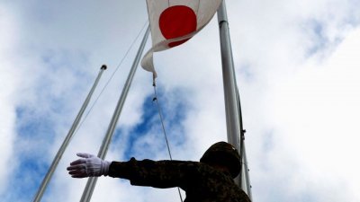 2022年4月21日,日本陆上自卫队（JGSDF）的一名成员在冲绳县宫古岛的陆上自卫队宫古营升起日本国旗。(图取自路透社档案照)