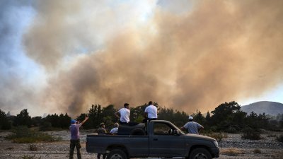 民众周二站在皮卡车上，在希腊罗德岛瓦蒂村附近观察野火。（图取自法新社）