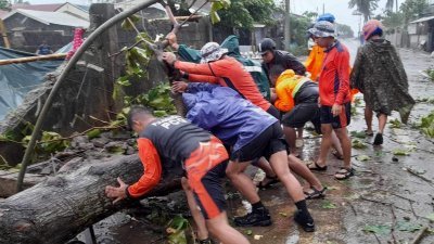 菲律宾海岸警卫队人员周三在卡加延省布吉，移走被台风吹倒的大树。（图取自菲律宾海岸警卫队/路透社）