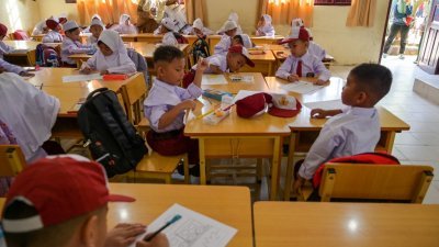 在印尼班达亚齐一所小学，7月17日是小一新生报到的第一天，一群一年级学生在班上适应校园的情况。（图取自法新社）