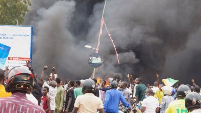 发起政变的尼日尔总统卫队的数百名支持者，当地时间周四聚集在首都尼亚美国民议会前焚烧执政党总部。（图取自路透社）