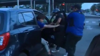 两名男子在十字路口截停一辆车之后，合力将车门打开，强行将车内华裔司机拉出车外。