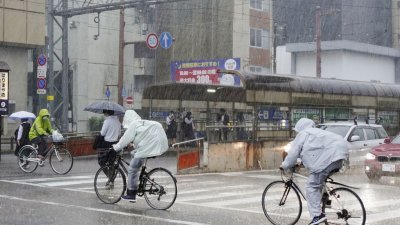台风“玛娃”临近日本之际，日本部分地区周五遭暴雨袭击，促使当局建议近130万人撤离。当天在日本四国岛南部的高知县高知市，人们穿著雨衣骑著自行车在大雨中前行。（图取自日本共同社/路透社）