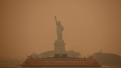 美国纽约地标自由女神像，当地时间周二笼罩在一片橙黄的烟霾空气中。（图取自路透社）