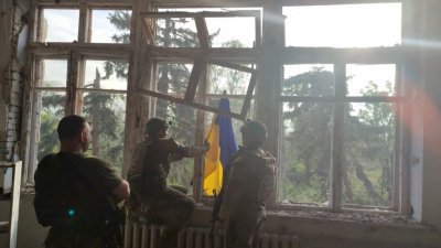 乌克兰士兵在反攻顿涅茨克收复的第一个村庄布拉戈达特内的一栋建筑物，挂上乌克兰国旗。（图取自68th Separate Hunting Brigade 'Oleksy Dovbusha'/路透社）