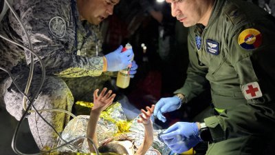 哥伦比亚空军的士兵，当地时间周五（9日）在飞机上，为哥伦比亚坠机事故中幸存的儿童提供医疗救助。（图取自哥伦比亚空军/路透社）