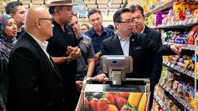 郑立慷(右)在科艺部秘书长拿督阿米鲁丁（左）、Retailetics 有限公司联合创办人马尼拉惹的陪同下，测试智能购物车的功能。