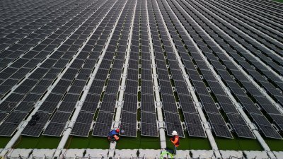 以色列一家可再生能源公司员工，当地时间周一在水库上安装太阳能电池板。（图取自路透社）