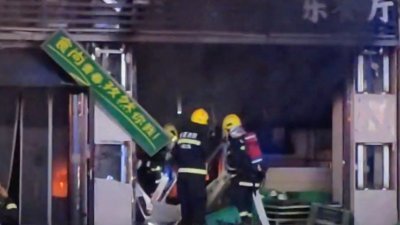 视频截图显示，消防员在烧烤店爆炸后的火灾现场救人。（图取自路透社）