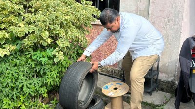 阿拉法在巡视住宅时，发现堆放在居民门前的旧轮胎有积水，对居民解释积水区或会成为蚊虫温床。