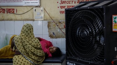 印度北方邦连日高温居高不下，日前在巴利亚区一家医院的急诊室里，一名病人躺在担架上获得亲戚的照料。（图取自路透社）