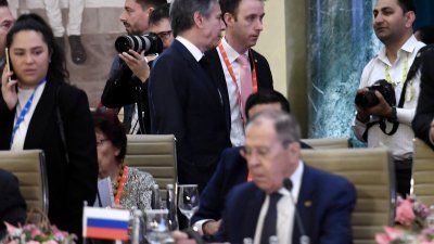 图为美国国务卿布林肯（左上）在G20外交部长会议经过俄罗斯外长拉夫罗夫（下）身后。（图取自路透社）