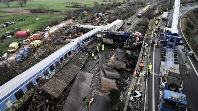 周四，在希腊中部拉里萨发生火车相撞事故后的第二天，警察和救援人员检查了一辆被压扁的货运火车残骸。（图取自法新社）