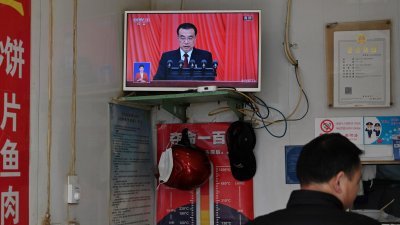 中国首都北京市一家餐馆的电视，正播放中国总理李克强在人大会议上作政府工作报告。（图取自法新社）