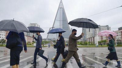 朝鲜民众雨中撑伞，在首都平壤街头走过。（图取自共同社/路透社）
