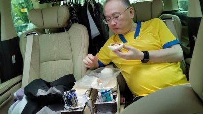 为了能节省赶往亚依淡选区的疏散中心进行巡视，魏家祥选择在车程中吃包子充饥。