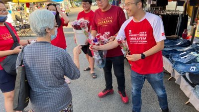 吴锡华（右）日前率领服务团队趁著国际妇女节前往巴刹派发500束玫瑰花给居民。右2为怡保市议员林智安。