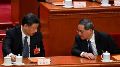 中国国家主席习近平（左）周日上午在全国人民代表大会第5次全体会议期间，与在前一天当选为中国国务院总理的李强交谈。（图取自法新社）