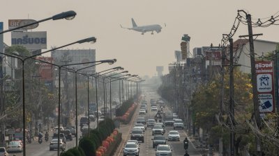 泰国近日空气污染严重，图为周五一架飞机飞过清迈一条繁忙的道路。（图取自法新社）