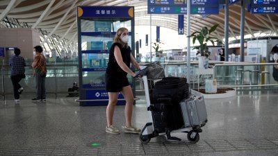 外国旅客推著行李，走过中国上海的浦东机场。（路透社档案照）