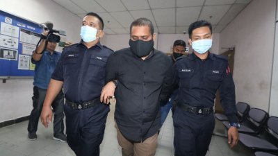 慕惹迪兰（中）在庭警的押送下步入法庭面控。