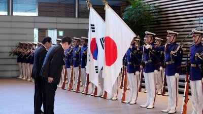 韩国总统尹锡悦和日本首相岸田文雄，周四在欢迎仪式检阅仪仗队期间，一起向韩国和日本的国旗鞠躬。（图取自路透社）
