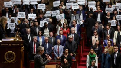 左翼议员对刚抵达国民议会的法国总理博尔内（左）报以嘘声，并举起标语抗议。（图取自路透社）