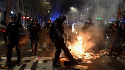 在法国政府根据宪法第49.3条未经表决实施养老金改革后，全法各地在上周六爆发激烈的警民冲突。在首都巴黎，一名法国宪兵试图踩灭示威者放的火。（图取自法新社）