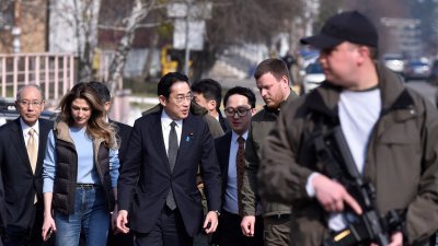 日本首相岸田文雄（后排中）周二走访乌克兰的布查镇，可见乌克兰派出的武装人员给予保护。（图取自法新社）