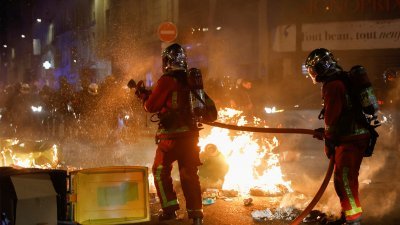 反对养老金改革法案的示威者，在法国首都巴黎点燃因罢工堆积在路旁的垃圾，消防员赶紧灭火。（图取自路透社）
