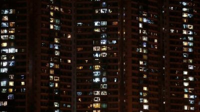 香港屯门附近一栋公寓楼，住户在晚上亮起了灯。（图取自路透社）