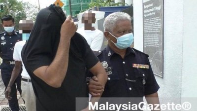 36岁被告（左）被押上法庭时，以外套遮脸。（图取自MalaysiaGazette）。
